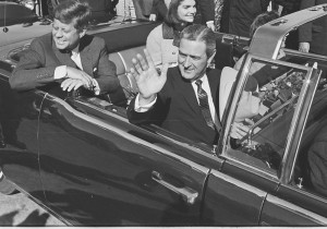 JFK, Jackie, and Governor Connally wave to the crowd as they pull out of Love Field to begin the motorcade.